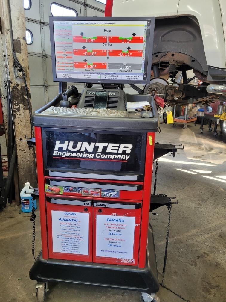 Hunter Engineering wheel alignment machine with red cabinet and monitoring display screen in automotive repair garage