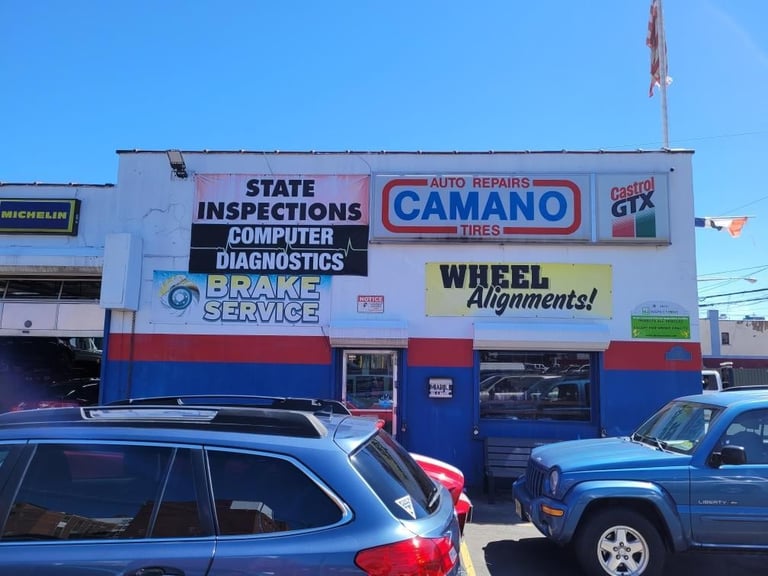Auto repair shop storefront with blue and red exterior displaying signs for state inspections, computer diagnostics, brake service, and wheel alignments